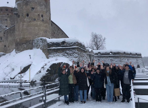 Die Schülerinnen und Schüler beim Besuch in Finnland vor der Burg Olavinlinna, in teils schneebedeckter Umgebung